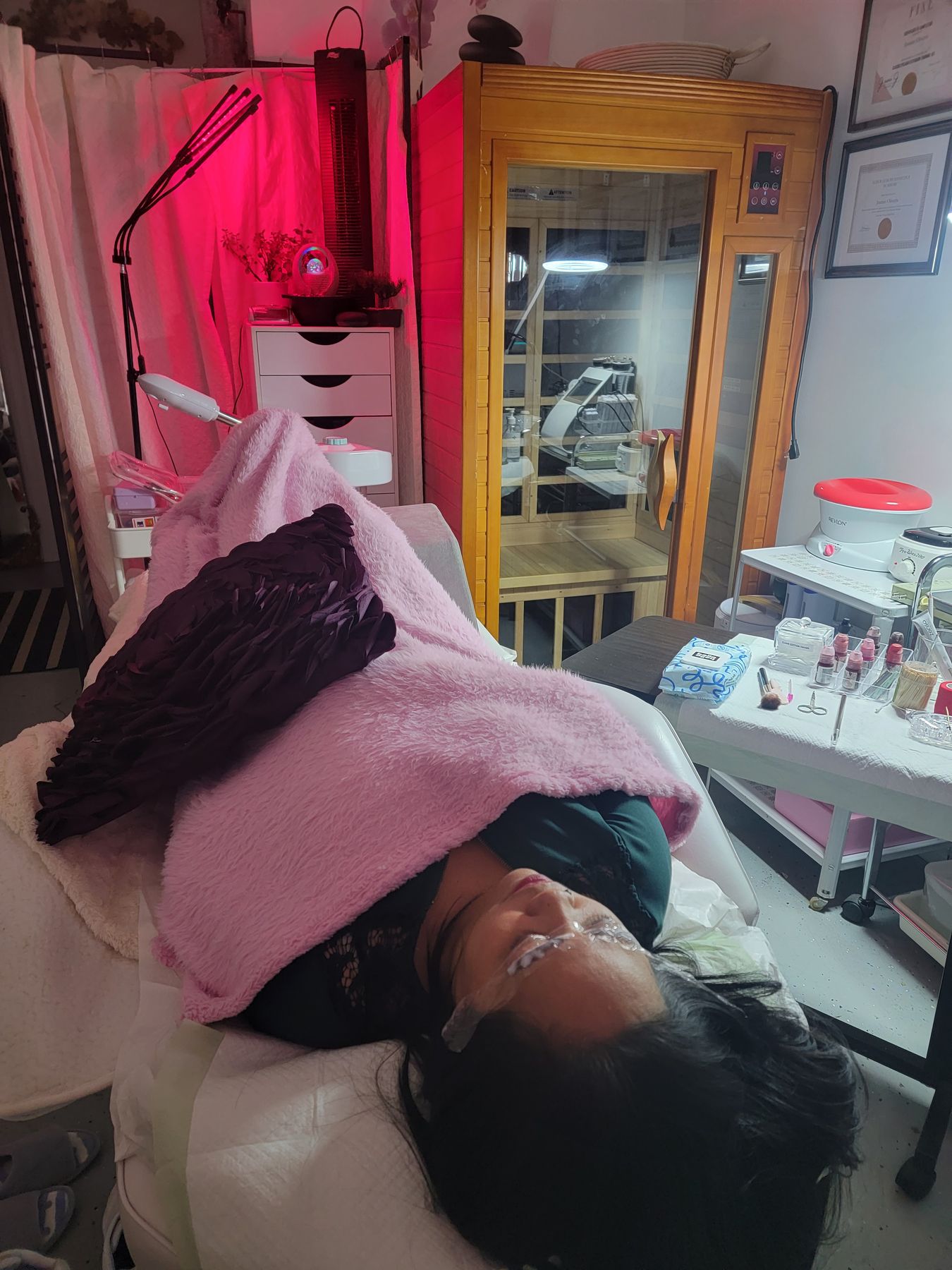Facial treatment under warm red light beside the sauna cabin