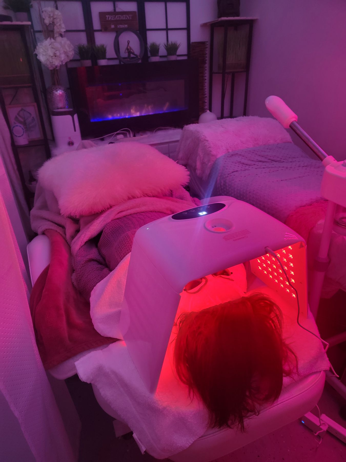 Red LED treatment glowing in the pink-lit spa room