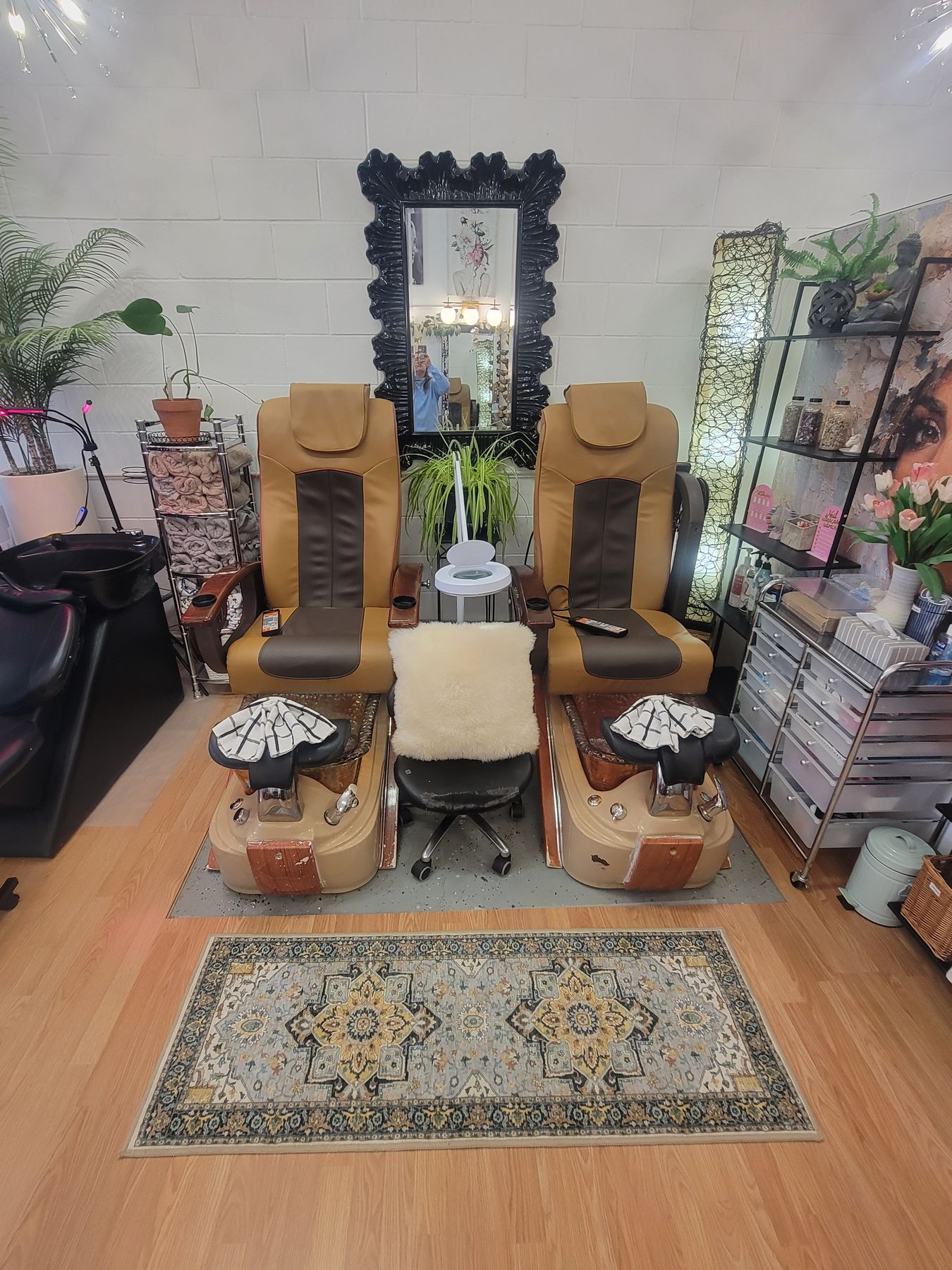 Two leather spa pedicure chairs below a black baroque mirror