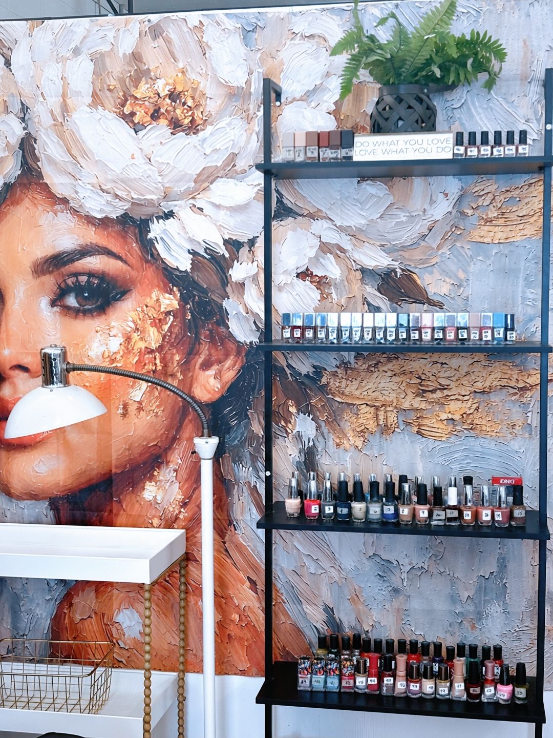 Shelves of nail polish beside a large floral mural